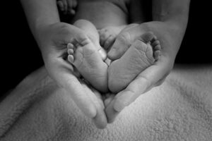 Baby feet surrounded by momma's hands in shape of a heart