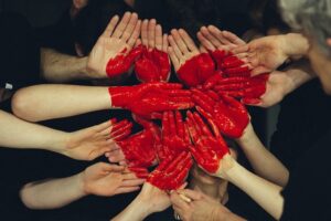 many hands all forming one big red heart together
